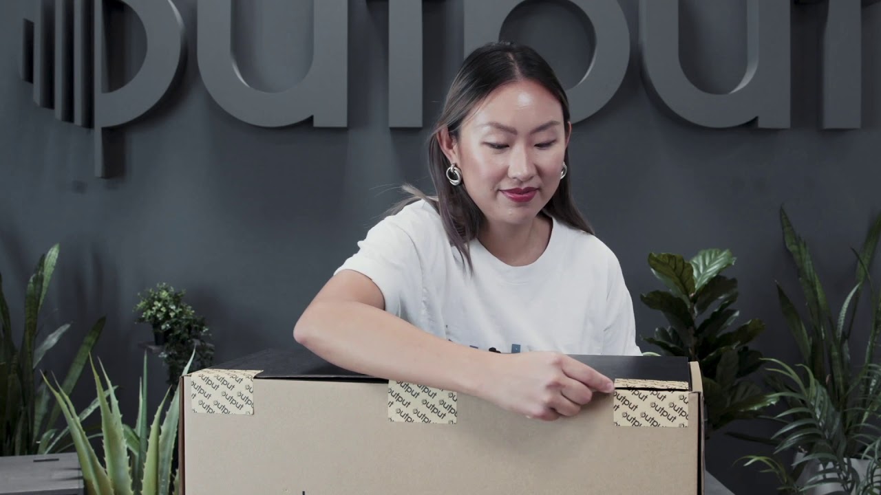 Woman unboxing Output Frontier studio monitor speakers