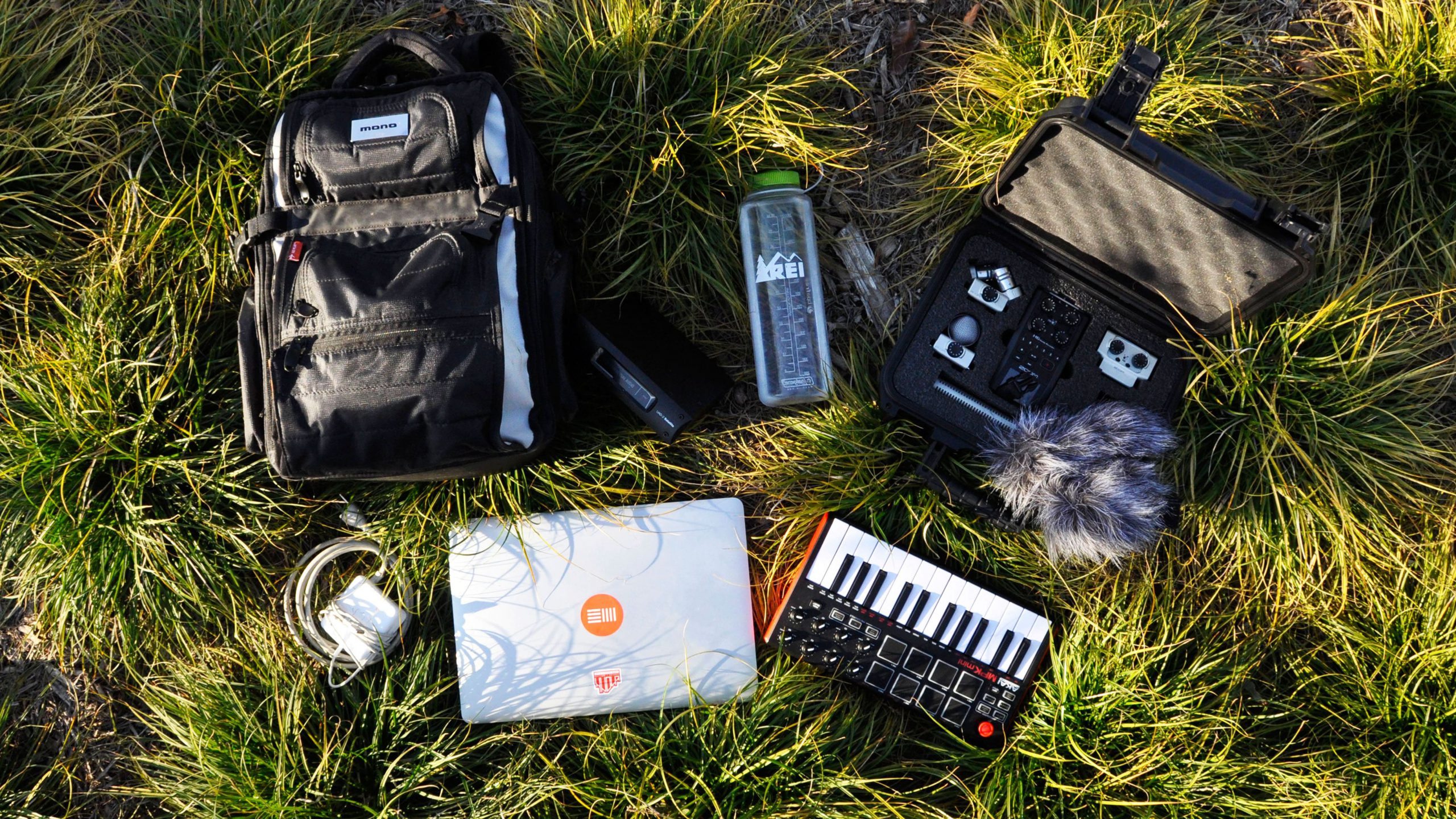 Travel essentials for musicians, with various pieces of gear for sound design and sound recording, including a laptop, cables, keyboard, and Zoom H6