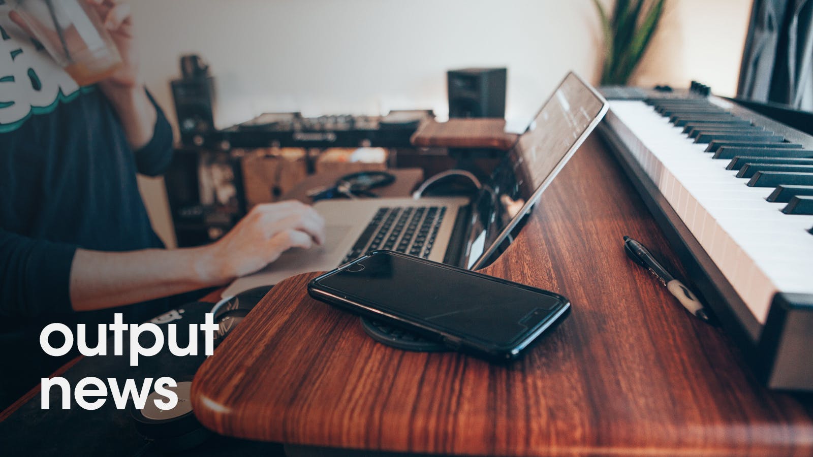 Musician at home working on laptop computer with keyboard in background