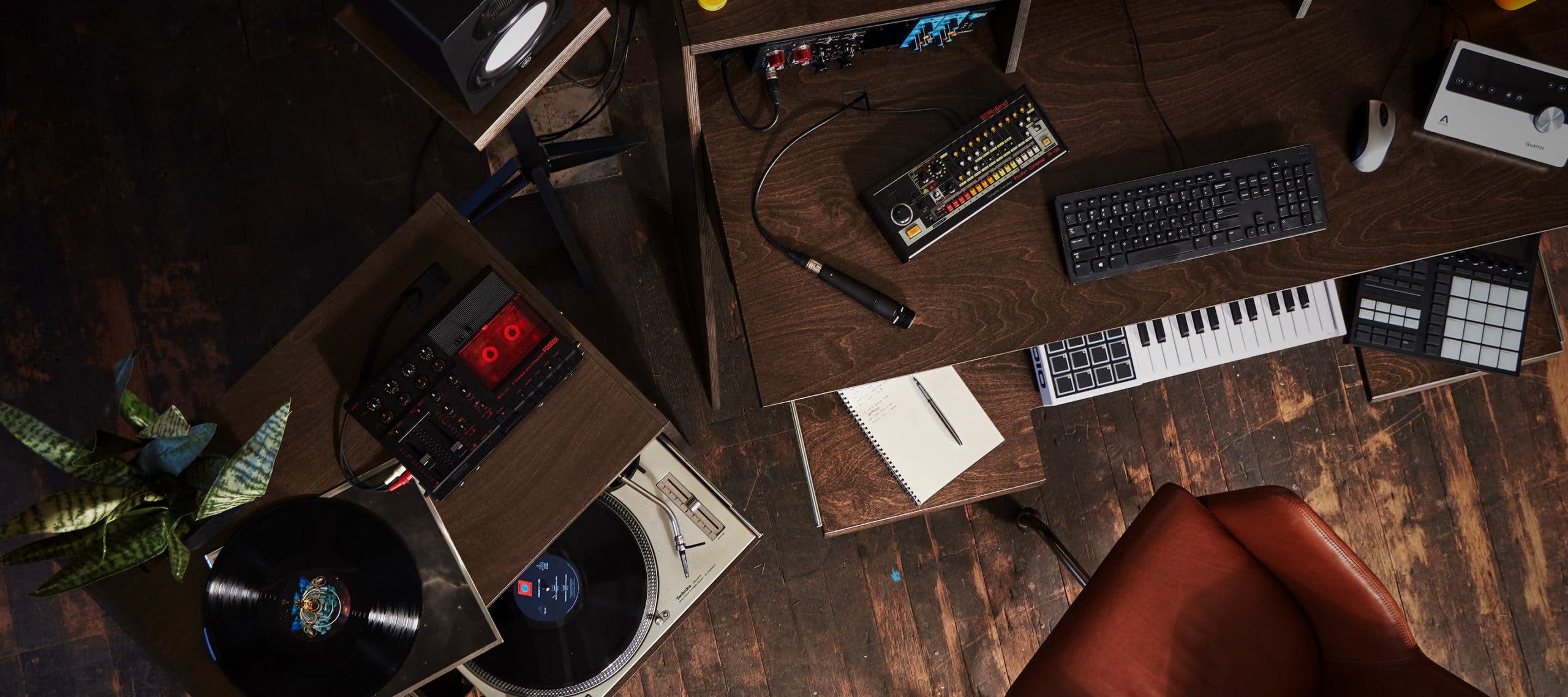 Aerial view of studio setup with brown Output Platform desk, brown Output Sidecar accessory holding turntable, MIDI controller, and keyboard.
