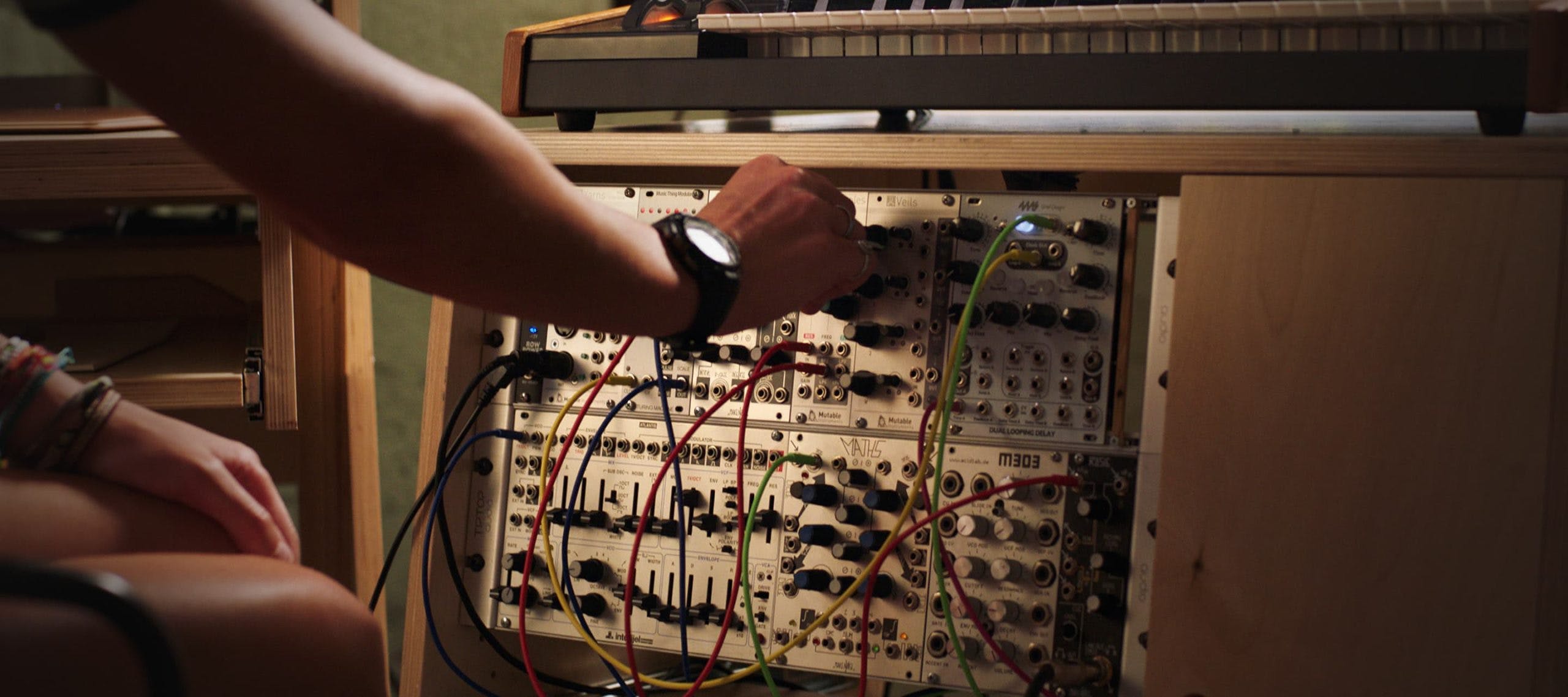 Person using analog synth held in natural color Output Sidecar accessory.