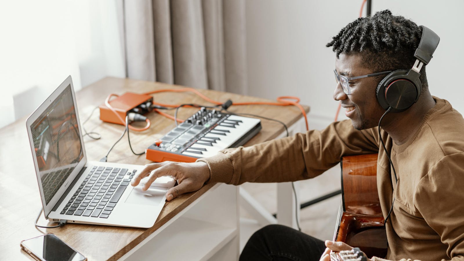 Man using music production software and playing guitar